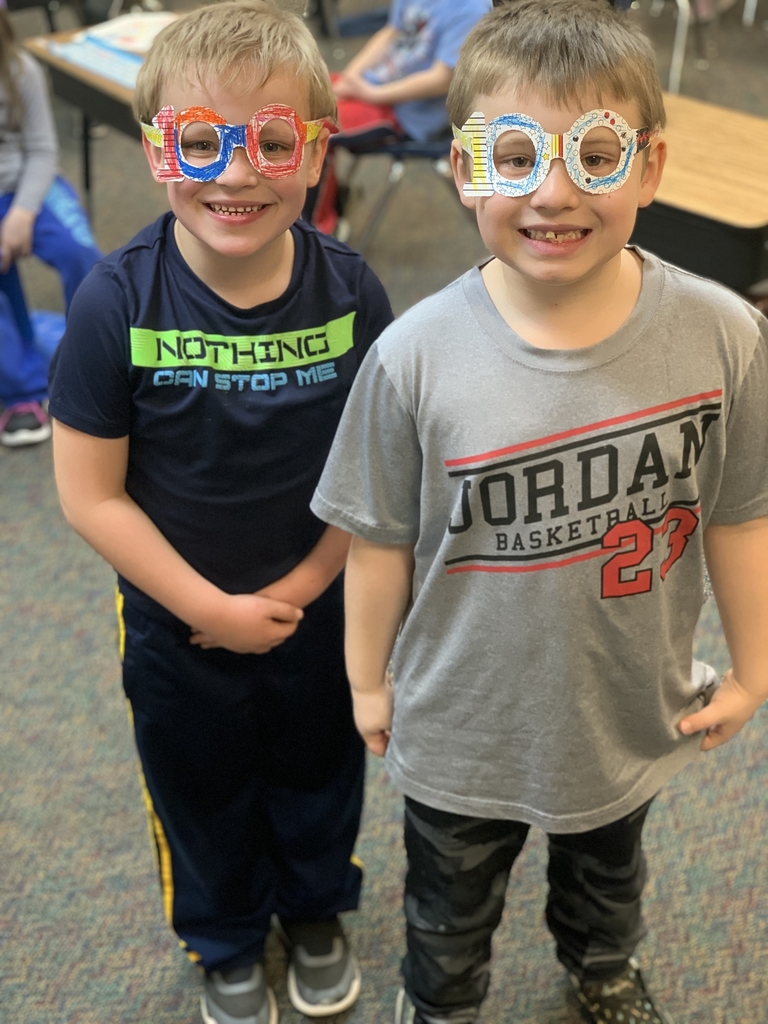 Two young students wearing paper glasses