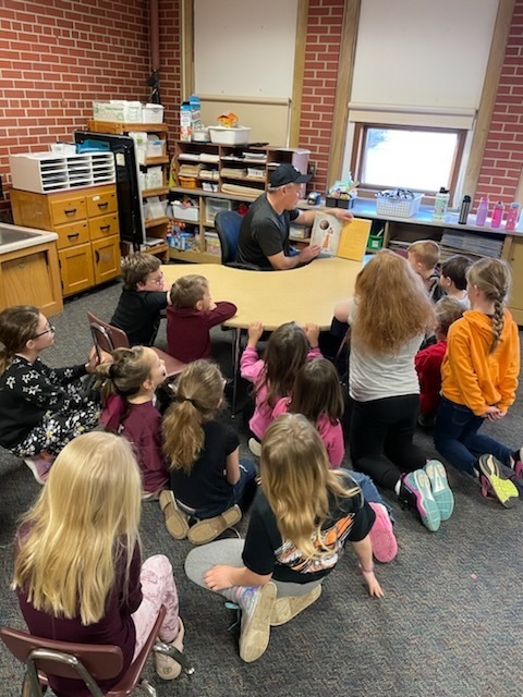 1st grade students listening to a guest reader.
