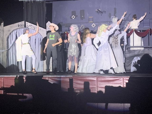 Students on stage in costume performing.