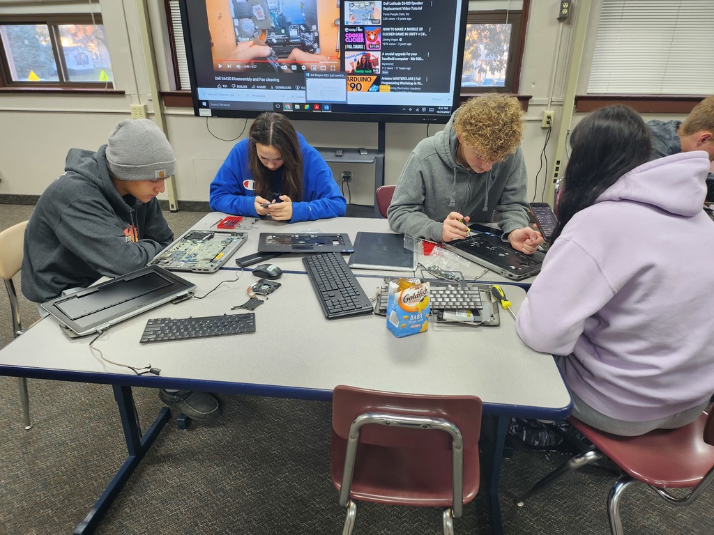 four students around table working on computers