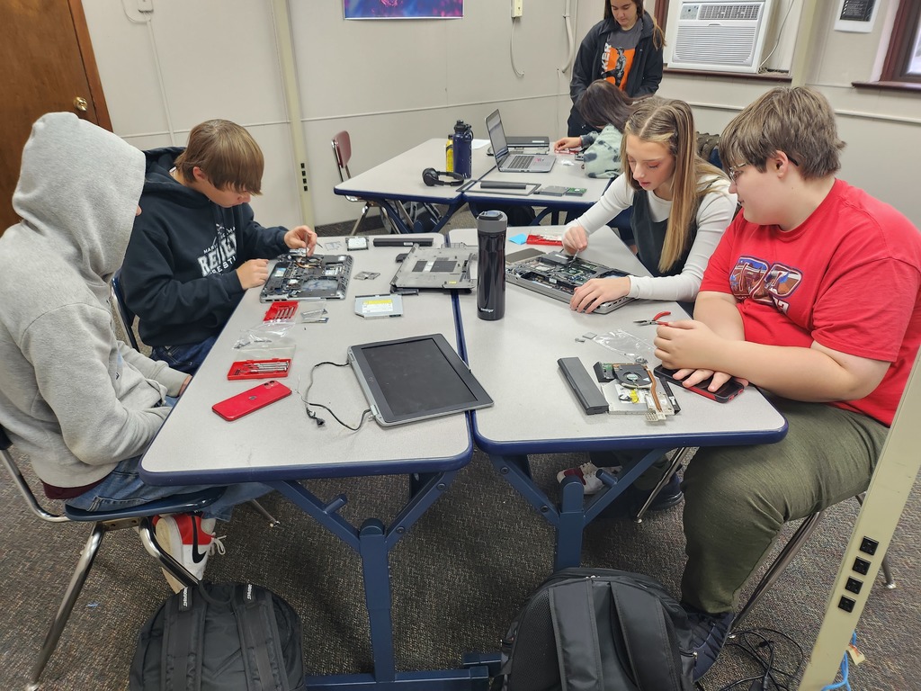 four students around table working on computers
