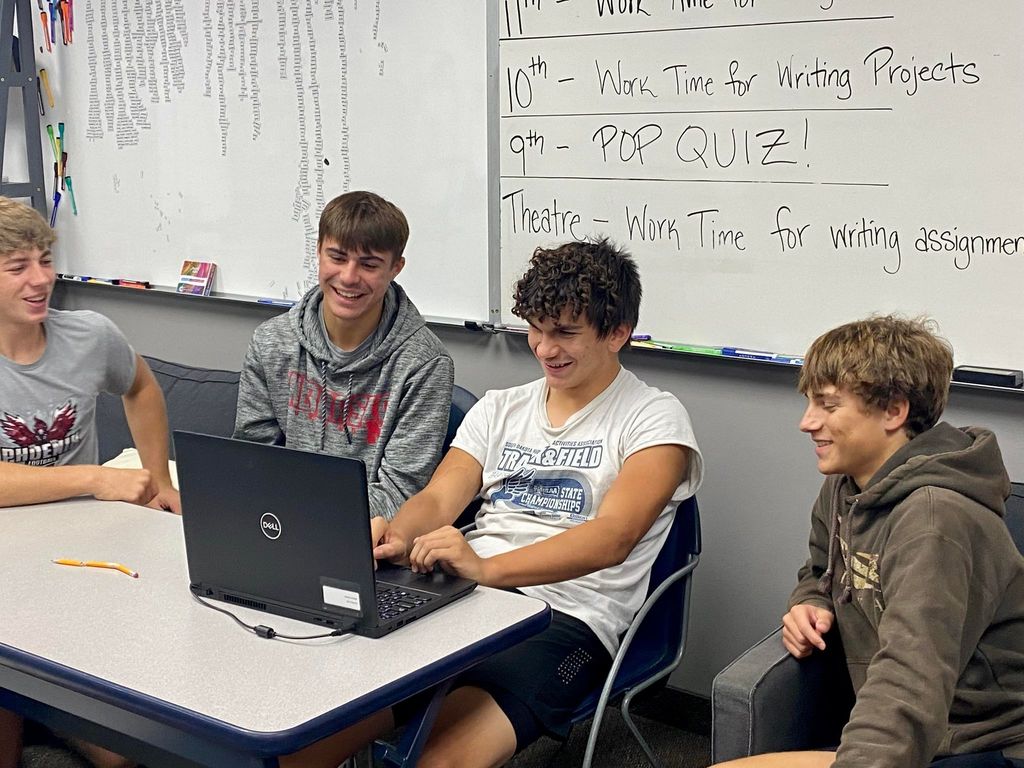 4 boys sitting in class by laptop