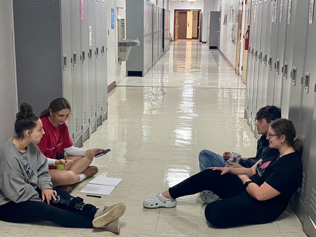 4 students sitting in hallway